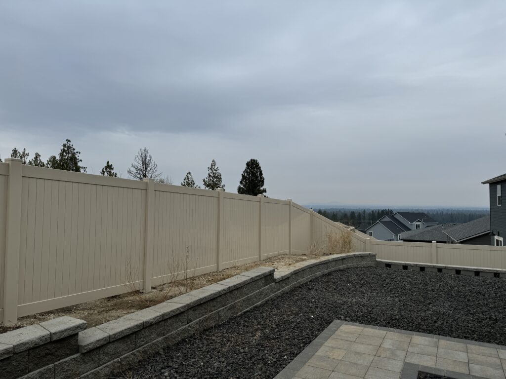 Tan vinyl privacy fence installation on South Hill Spokane property with panoramic city views, creating a secure boundary for newly landscaped backyard